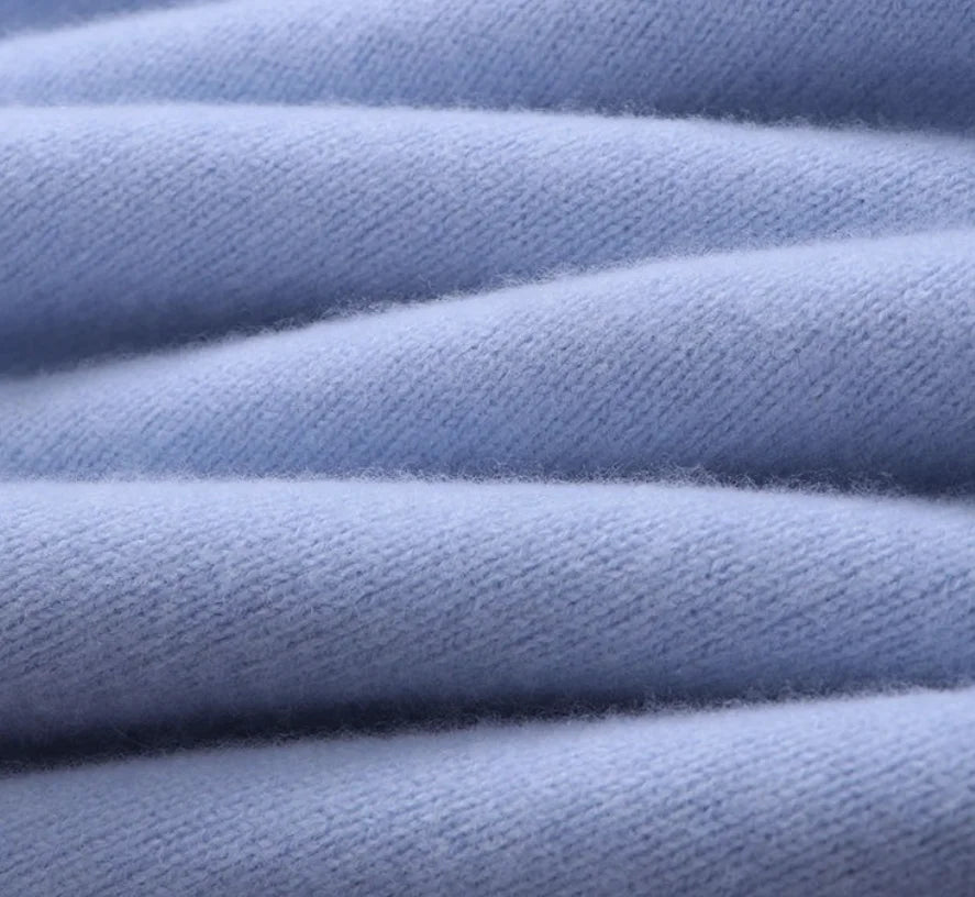 Suéter de caxemira na cor azul 1, com gola careca e mangas compridas, exibido em um cabide de madeira sobre um fundo branco.."