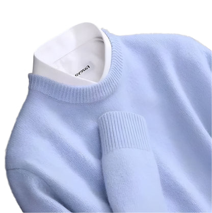 Suéter de caxemira na cor azul, com gola careca e mangas compridas, exibido em um cabide de madeira sobre um fundo branco.