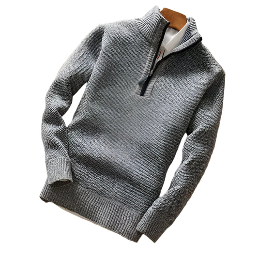 "Detalhe do suéter de malha usado com o zíper fechado, formando uma elegante gola alta que protege do frio."